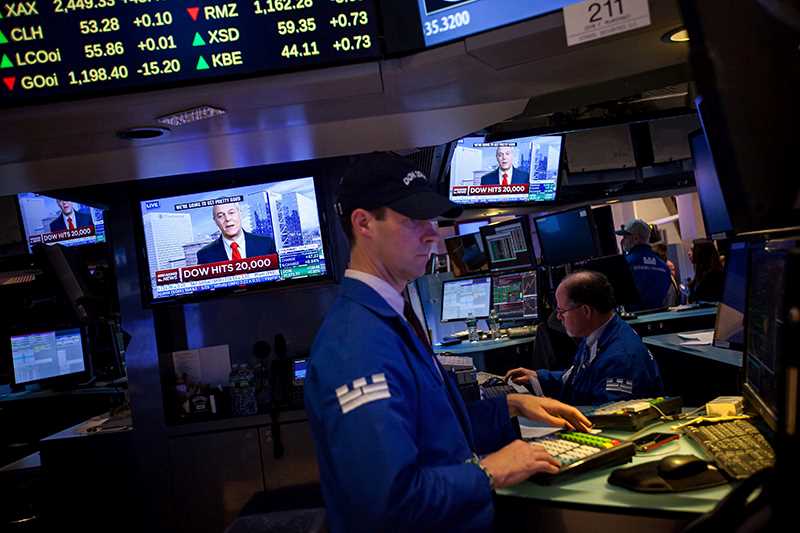 Trader på New York Stock Exchange står foran skærm, der viser da Dow Jones ramte 20.000