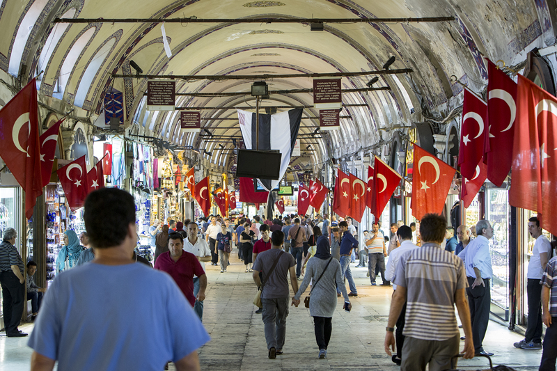 Folk går på et marked, hvor der er tyrkiske flag